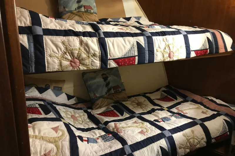 Slide: The Image of Bunk beds with nautical-themed quilts inside a 1976 Hatteras 53 Convertible yacht cabin. - 12