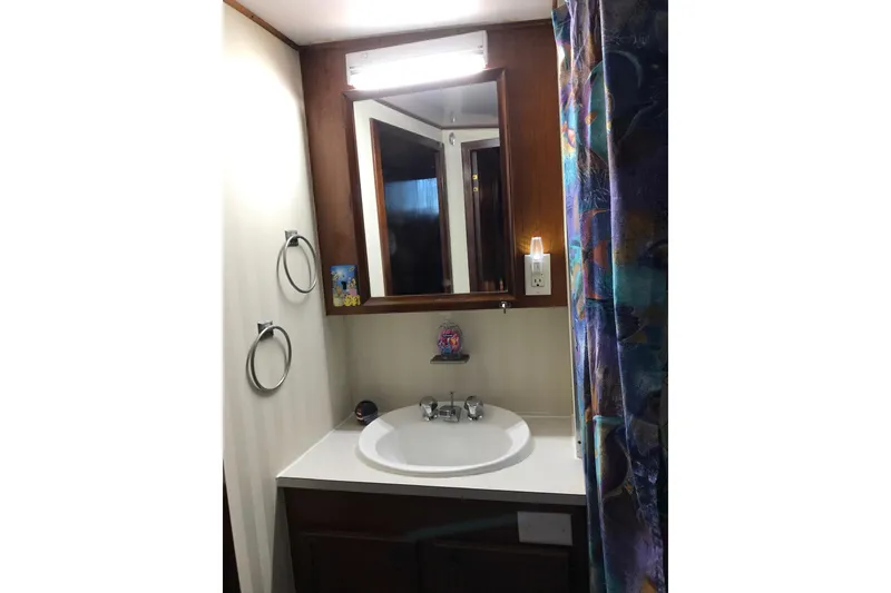 Slide: The Image of Bathroom vanity with mirror and colorful shower curtain on a 1976 Hatteras 53 Convertible yacht. - 16