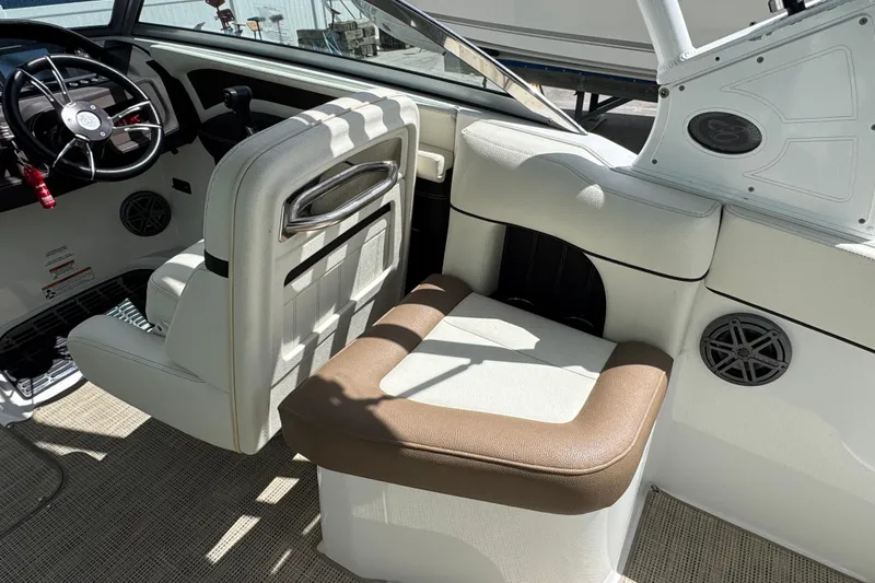 Slide: The Image of Interior of 2018 Cobalt 23SC boat with white and brown seating, steering wheel, and speakers. - 10