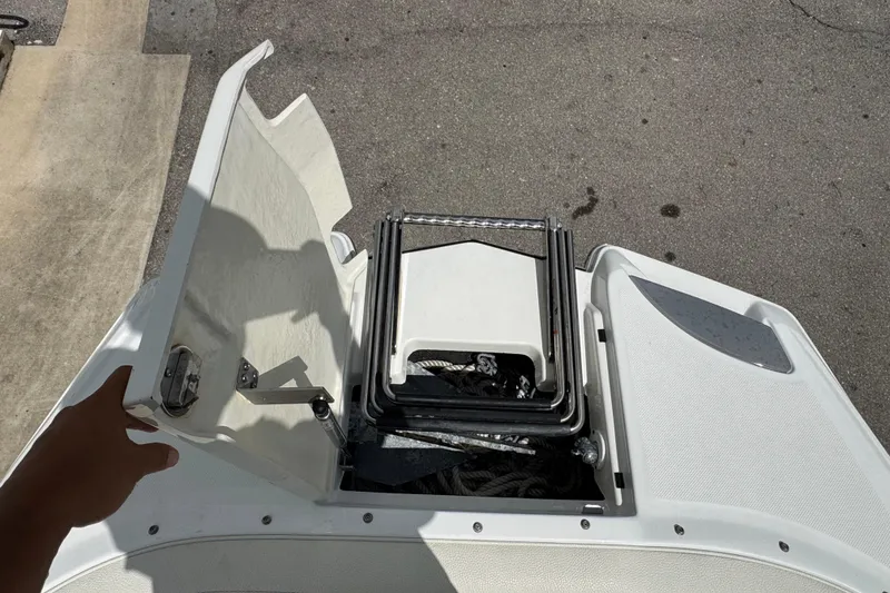 Slide: The Image of Open storage compartment on a 2018 Cobalt 23SC boat, showing a folded ladder. - 18