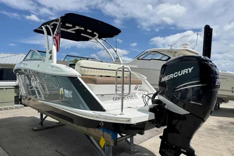 Slide: The Image of 2018 Cobalt 23SC boat with Mercury engine, docked under a blue sky. - 2