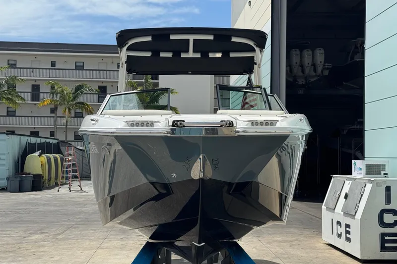 Slide: The Image of 2018 Cobalt 23SC boat docked outdoors, with palm trees and buildings in the background. - 4