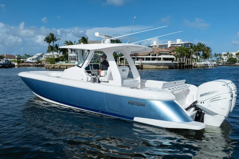 Slide: The Image of 2022 Intrepid 345 Nomad SE boat cruising on a sunny day near waterfront homes. - 12