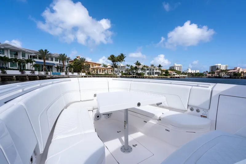 Slide: The Image of 2022 Intrepid 345 Nomad SE boat interior with luxurious seating and table, waterfront view. - 18
