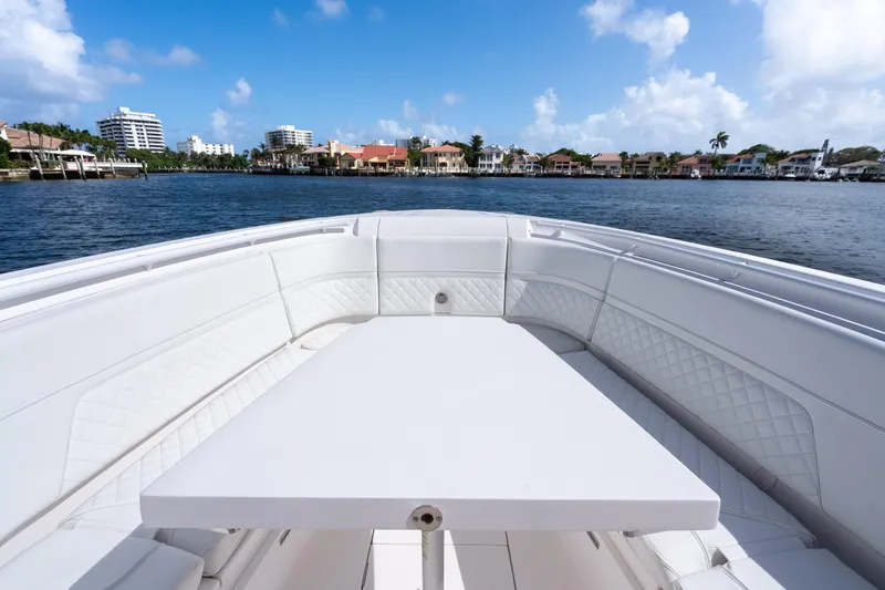 Slide: The Image of 2022 Intrepid 345 Nomad SE boat with spacious seating and table on calm water. - 20