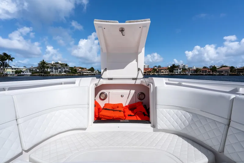 Slide: The Image of 2022 Intrepid 345 Nomad SE boat with open storage compartment and life jackets, under clear blue sky. - 22