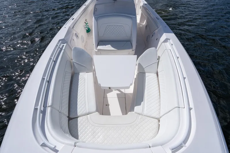 Slide: The Image of 2022 Intrepid 345 Nomad SE boat with luxurious white seating and table on open water. - 24