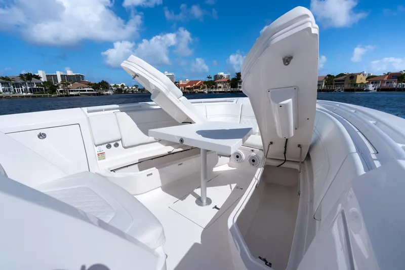 Slide: The Image of 2022 Intrepid 345 Nomad SE boat interior with seating and table, under a clear blue sky. - 25