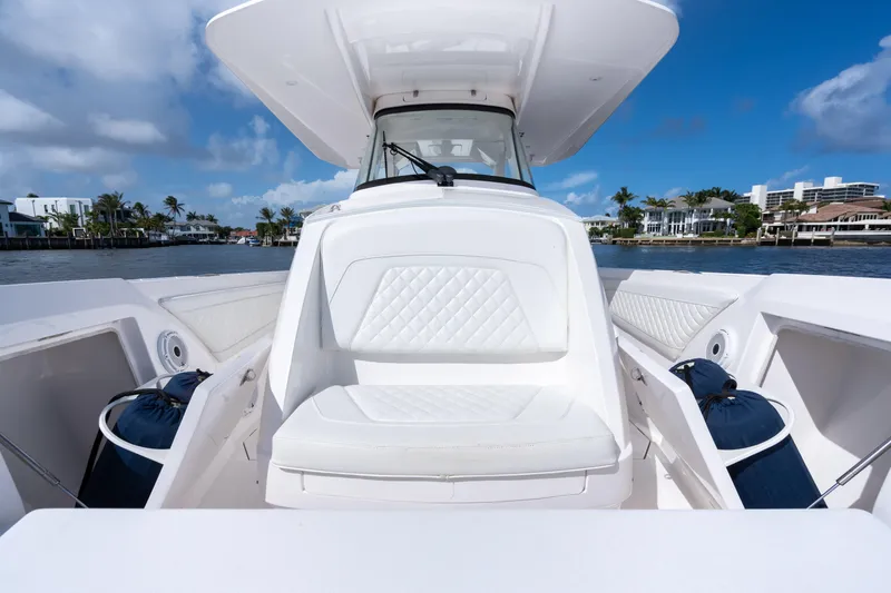 Slide: The Image of 2022 Intrepid 345 Nomad SE boat with white seating, on a sunny waterfront. - 26