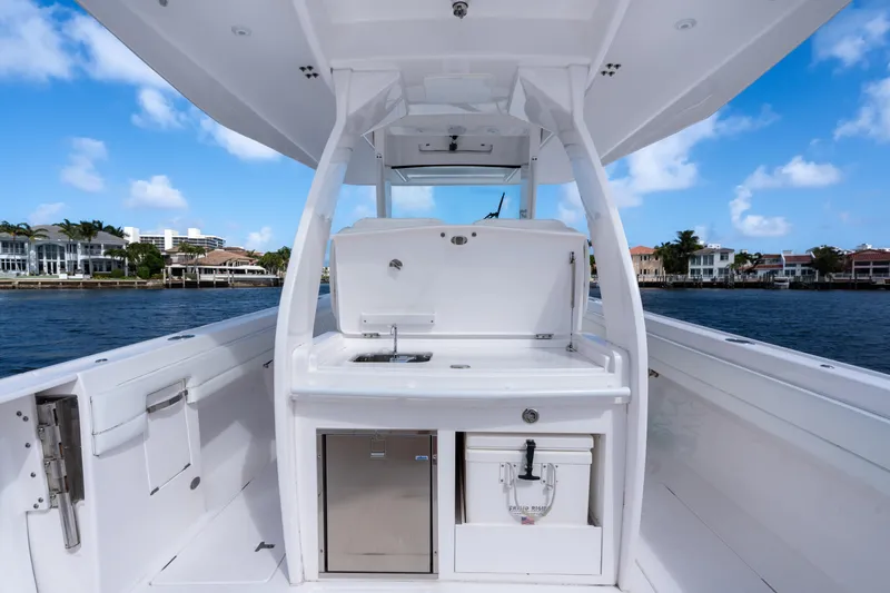Slide: The Image of 2022 Intrepid 345 Nomad SE boat interior with sink and storage, docked by waterfront homes. - 29