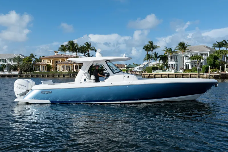 Slide: The Image of 2022 Intrepid 345 Nomad SE boat cruising near waterfront homes under blue skies. - 5