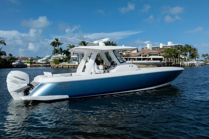 Slide: The Image of 2022 Intrepid 345 Nomad SE boat on water, with blue hull and twin Mercury engines. - 6