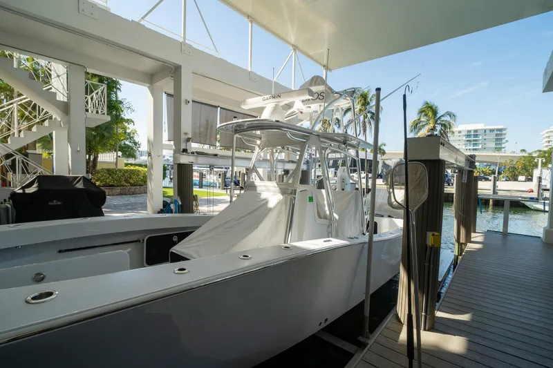 Slide: The Image of 2026 Conch 33 boat docked in a marina with palm trees and modern buildings. - 49