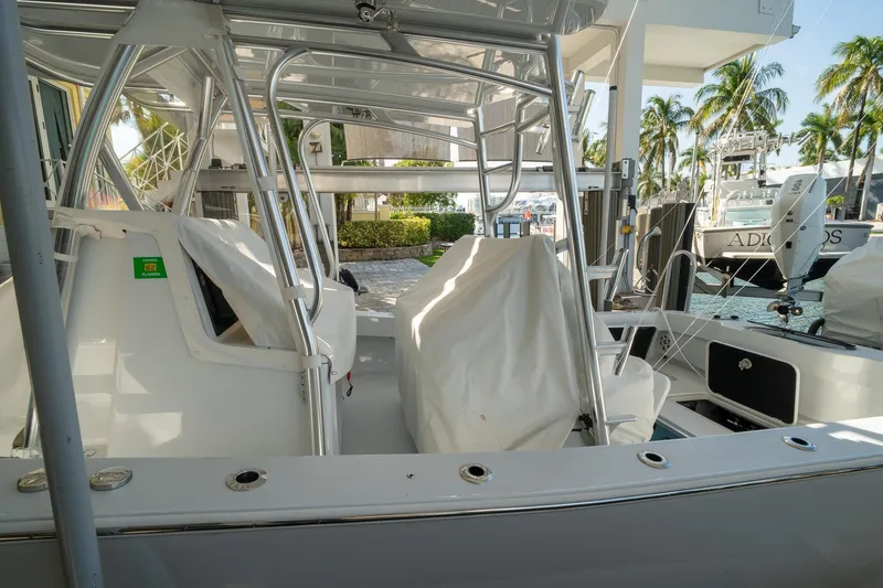 Slide: The Image of 2026 Conch 33 boat interior with covered seats, docked near palm trees and water. - 50