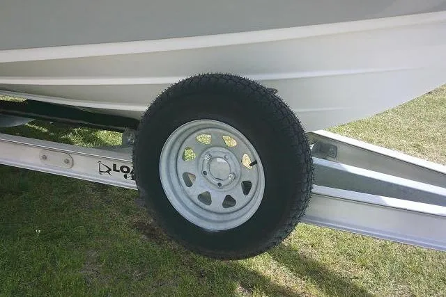 Slide: The Image of Trailer wheel of 2022 Sportsman Tournament 214 Bay Boat on grass. - 11