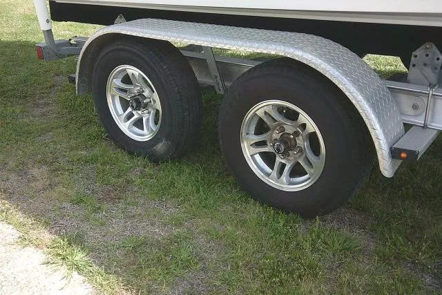 Slide: The Image of Trailer wheels of a 2022 Sportsman Tournament 214 Bay Boat on grass. - 12
