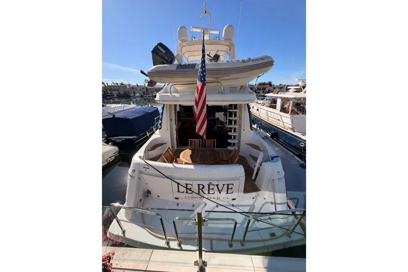 Slide: The Image of 1999 Carver 530 Voyager Pilothouse yacht docked, featuring an American flag and upper deck dinghy. - 4