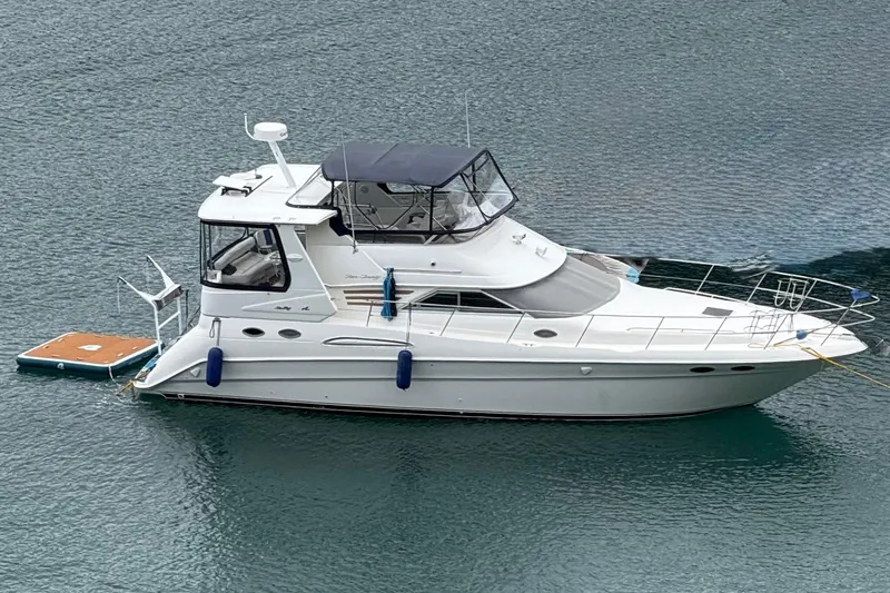 The Image of 1998 Sea Ray 420 Aft Cabin yacht anchored on calm water. - 1
