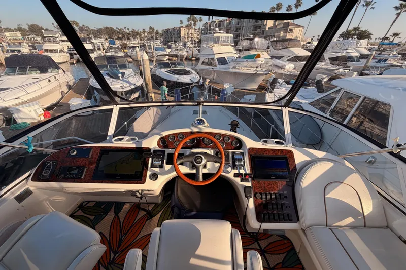 Slide: The Image of 1998 Sea Ray 420 Aft Cabin yacht helm with marina view, featuring luxury controls and seating. - 29