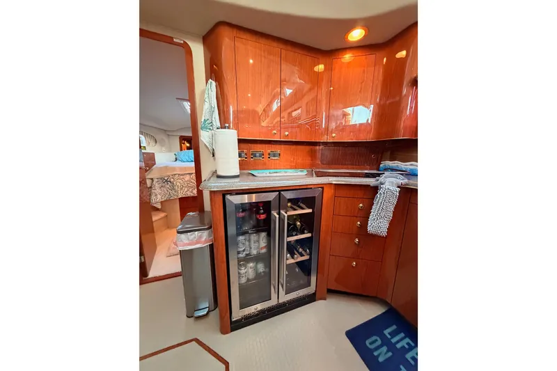 Slide: The Image of 1998 Sea Ray 420 Aft Cabin interior with wooden cabinets and mini fridge. - 51
