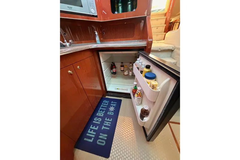 Slide: The Image of 1998 Sea Ray 420 Aft Cabin kitchen with open fridge and nautical-themed mat. - 54