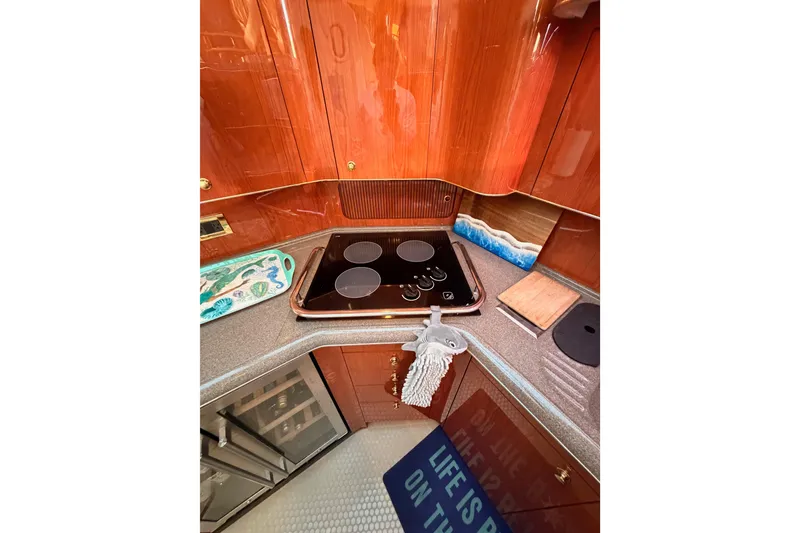 Slide: The Image of 1998 Sea Ray 420 Aft Cabin kitchen with stove, wooden cabinetry, and countertop accessories. - 56