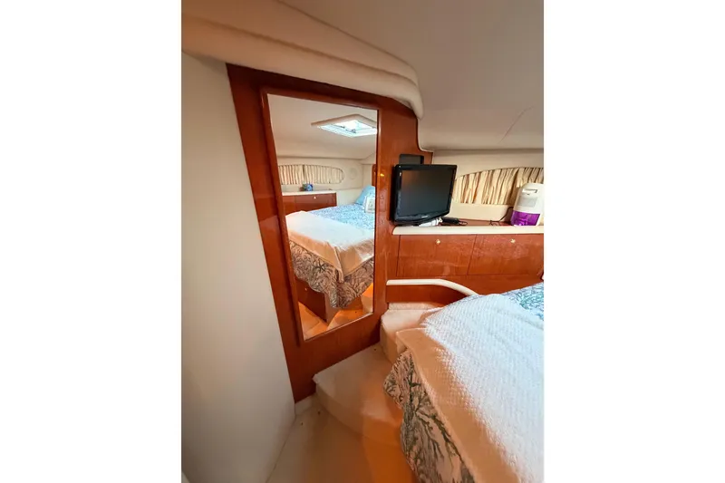 Slide: The Image of 1998 Sea Ray 420 Aft Cabin interior with bed, TV, and wooden accents. - 64