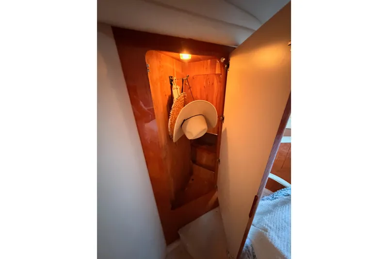 Slide: The Image of 1998 Sea Ray 420 Aft Cabin closet with hats and warm lighting. - 65