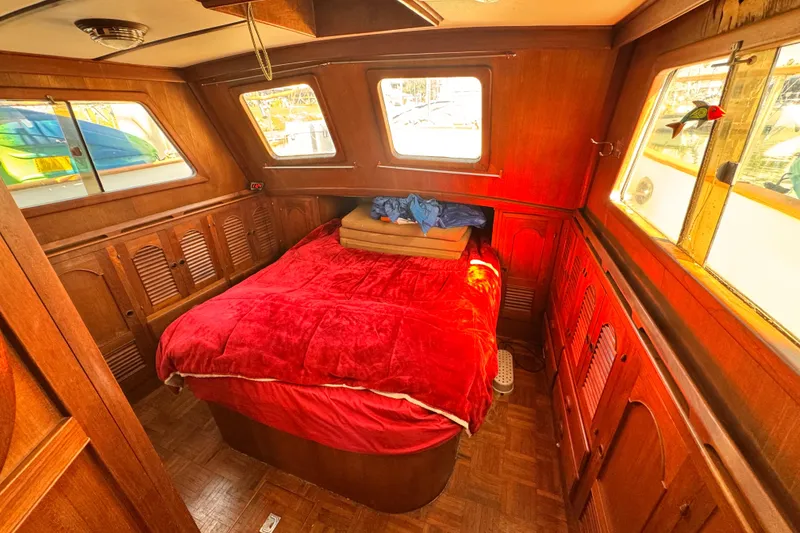 Slide: The Image of Cozy 1980 Hershine Trawler cabin with red bedding and wooden interior. - 10