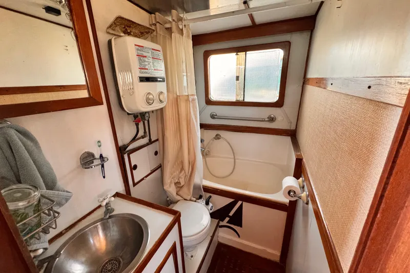 Slide: The Image of 1980 Hershine Trawler bathroom with sink, toilet, and shower in compact wooden interior. - 13