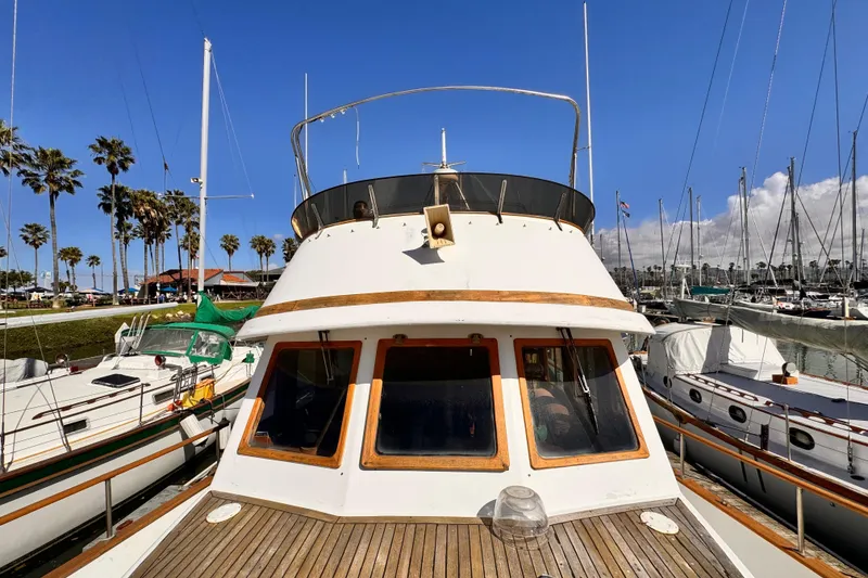 Slide: The Image of 1980 Hershine Trawler deck with chairs and cushions in a marina setting. - 17