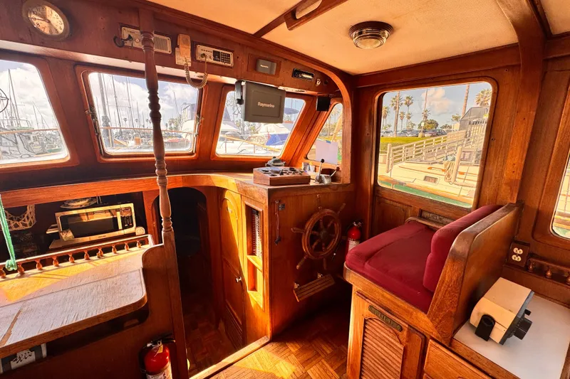 Slide: The Image of 1980 Hershine Trawler interior with wooden helm, vintage equipment, and marina view. - 5