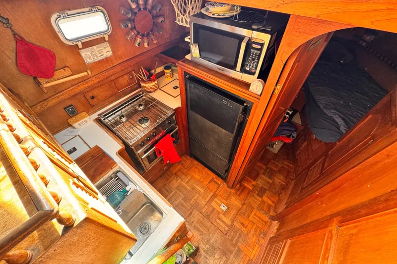 Slide: The Image of 1980 Hershine Trawler kitchen with stove, microwave, and wooden cabinetry. - 7