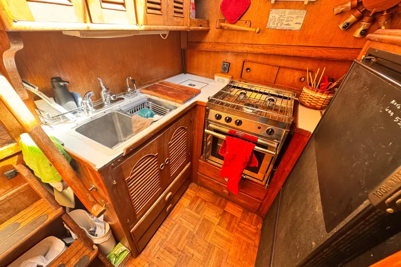 Slide: The Image of 1980 Hershine Trawler kitchen with wooden cabinetry, stove, and sink. Cozy nautical design. - 8