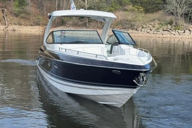 Slide: The Image of 2026 Formula 330 Crossover Bowrider I/O cruising on a calm lake near a wooded shoreline. - 26