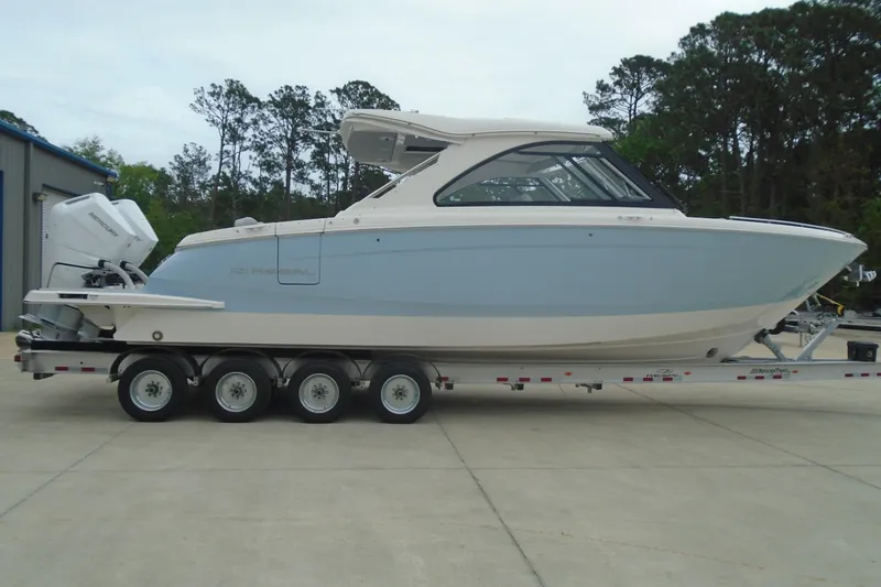 Slide: The Image of 2026 Regal LX36 boat on trailer, side view, outdoors with trees in background. - 2
