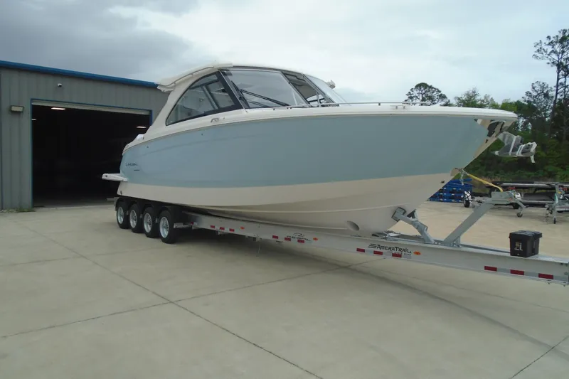 Slide: The Image of 2026 Regal LX36 boat on trailer outside a warehouse, ready for transport. - 3