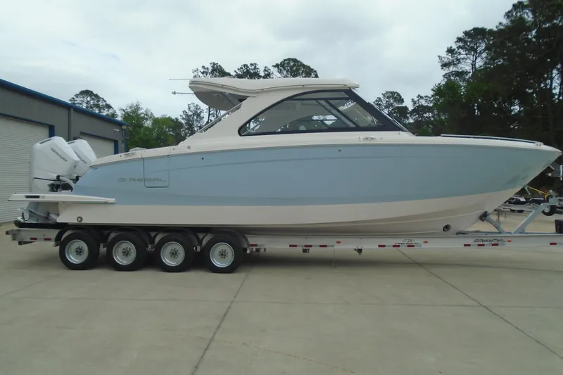 Slide: The Image of 2026 Regal LX36 boat on trailer, light blue hull, parked outdoors. - 32