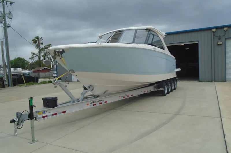 Slide: The Image of 2026 Regal LX36 boat on trailer outside a warehouse under cloudy skies. - 4