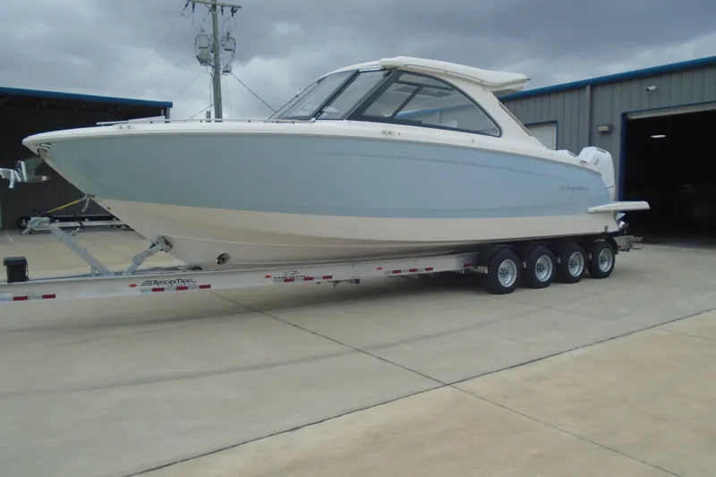 Slide: The Image of 2026 Regal LX36 boat on trailer, parked outside a warehouse under cloudy skies. - 5