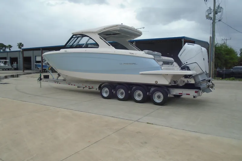 Slide: The Image of 2026 Regal LX36 boat on trailer, parked outdoors, showcasing sleek design and powerful engines. - 7