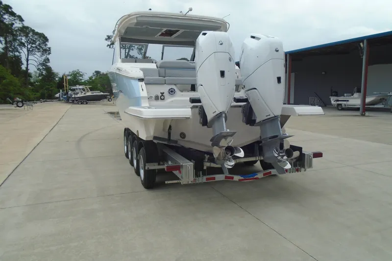 Slide: The Image of 2026 Regal LX36 boat on trailer with dual outboard motors in a marina setting. - 8