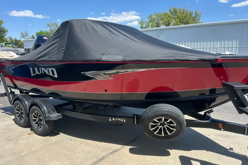 Slide: The Image of 2026 Lund 1875 Impact XS Sport boat with cover on trailer, parked outdoors. - 10