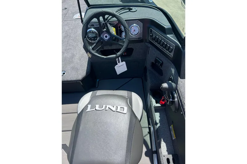 Slide: The Image of 2026 Lund 1875 Impact XS Sport boat interior with steering wheel and dashboard controls. - 18