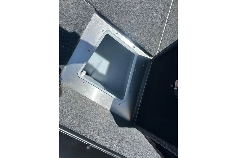 Slide: The Image of 2026 Lund 1875 Impact XS Sport boat storage compartment with carpeted interior. - 23