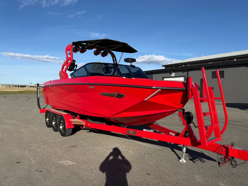 The Image of Red 2021 Nautique G25 boat on trailer in sunny weather. - 1