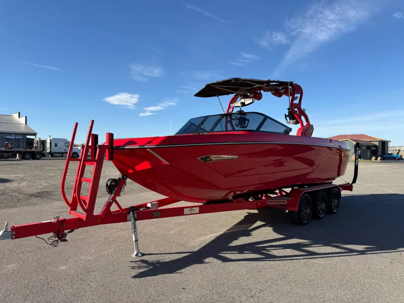 Slide: The Image of Red 2021 Nautique G25 boat on trailer under blue sky. - 7