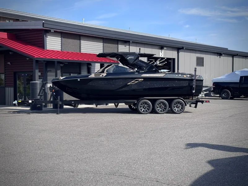 Slide: The Image of 2026 Centurion Ri245 boat on trailer outside building. - 29