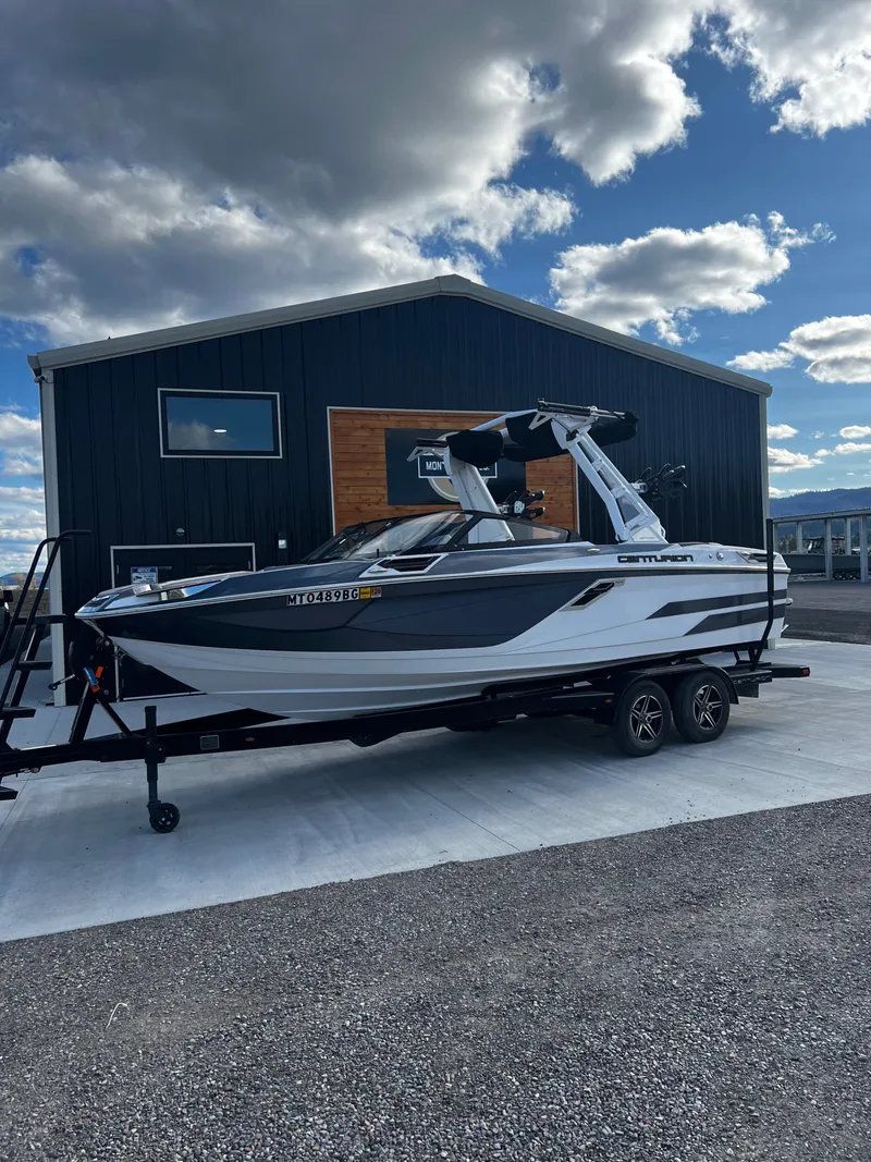 The Image of 2023 Centurion Ri230 boat on trailer in front of building. - 1