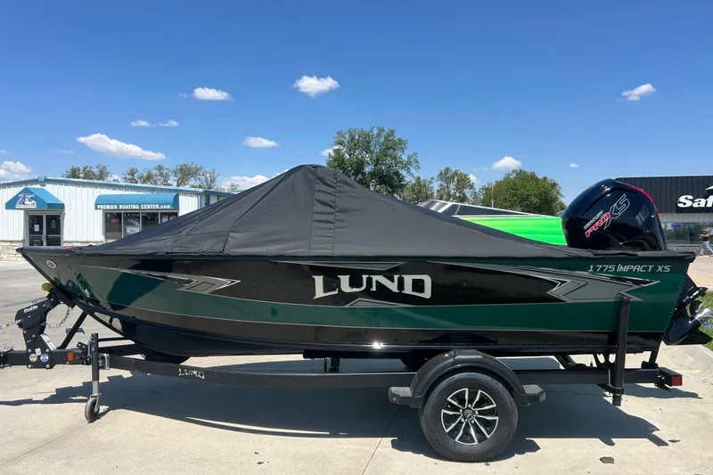 Slide: The Image of 2026 Lund 1775 Impact XS Sport boat with cover on trailer, outdoors under blue sky. - 5
